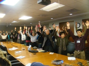 Participants raise their arms at Dr. Yang's meeting